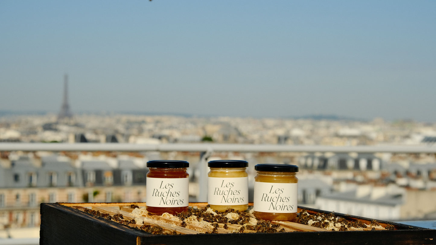 Pots de miel de Paris Les Ruches Noires posés sur une ruche ouverte avec vue sur la Tour Eiffel