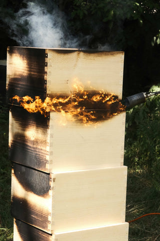 Ruche en bois en cours de carbonisation par flamme selon la méthode yakisugi - Les Ruches Noires