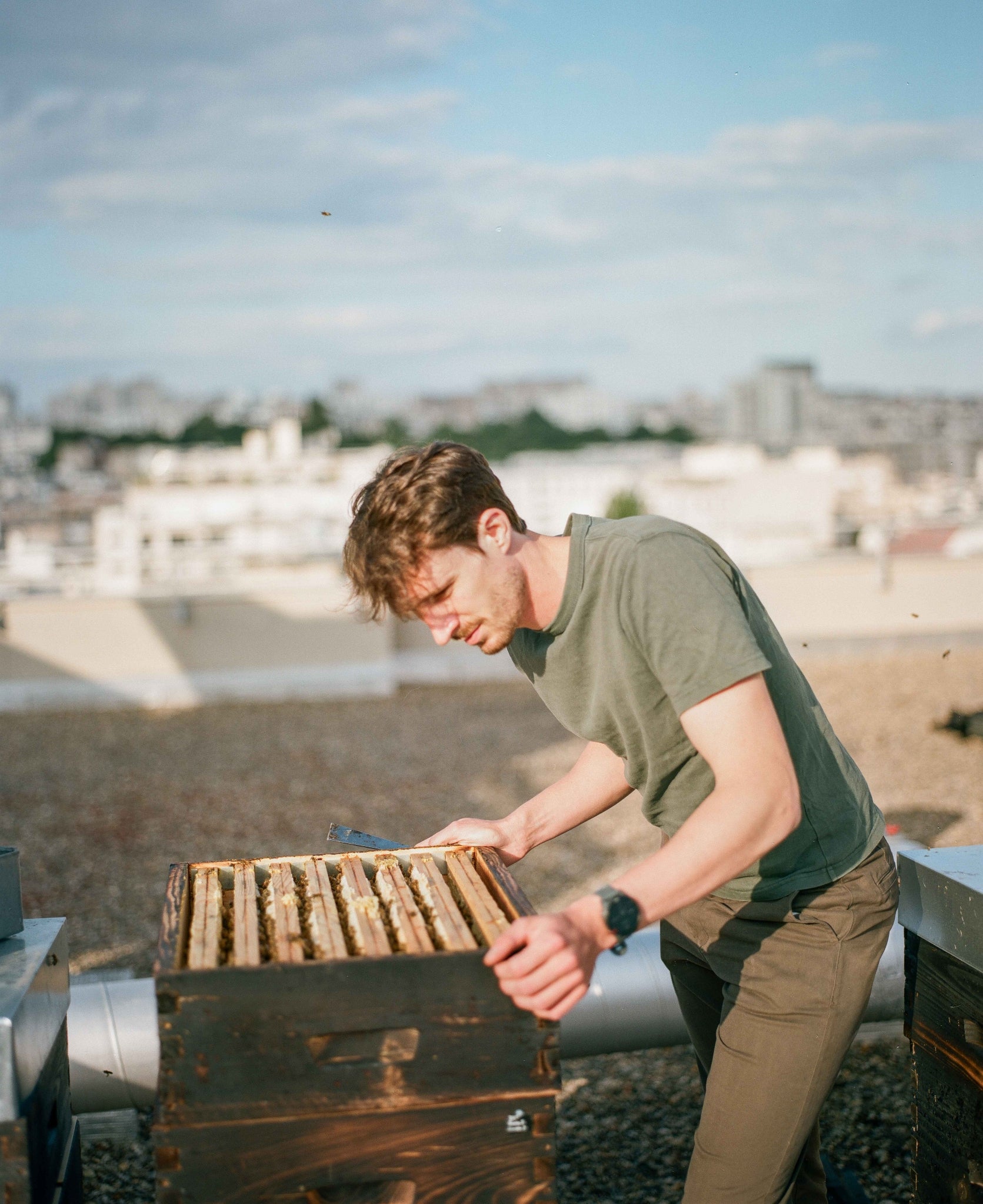 Apiculteur observant ses ruches sur un toit parisien - Les Ruches Noires - Etienne Coz