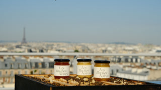 Pots de miel de Paris Les Ruches Noires posés sur une ruche ouverte avec vue sur la Tour Eiffel